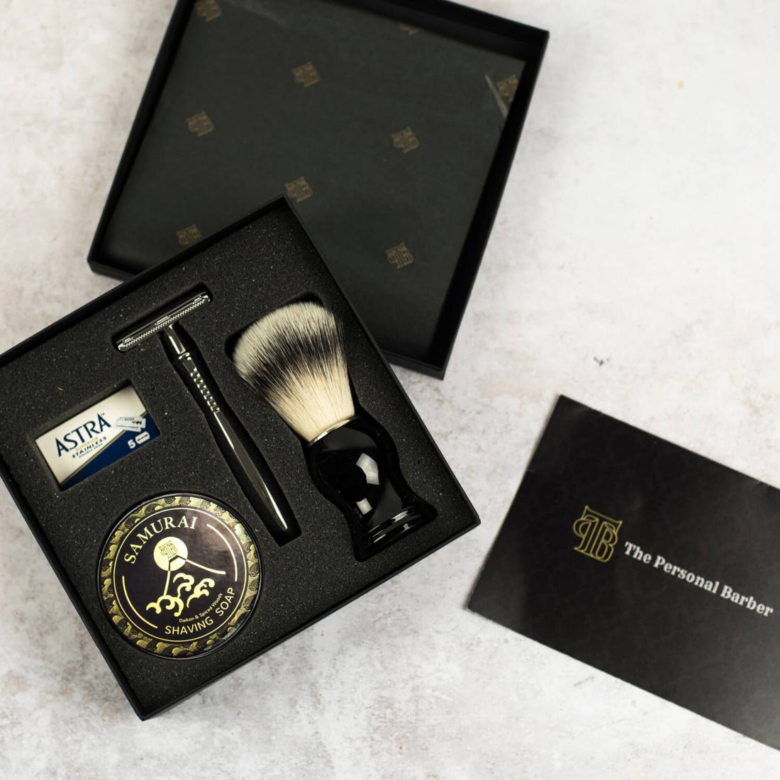 Top down view of open traditional shaving gift box set - shaving brush, premium safety razor, shaving soap, Astra razor blades with information card and instructions